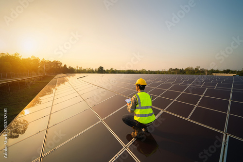 Portrait of engineer man or worker, people, with solar panels or solar cells on the roof in farm. Power plant with green field, renewable energy source in Thailand. Eco technology for electric power.