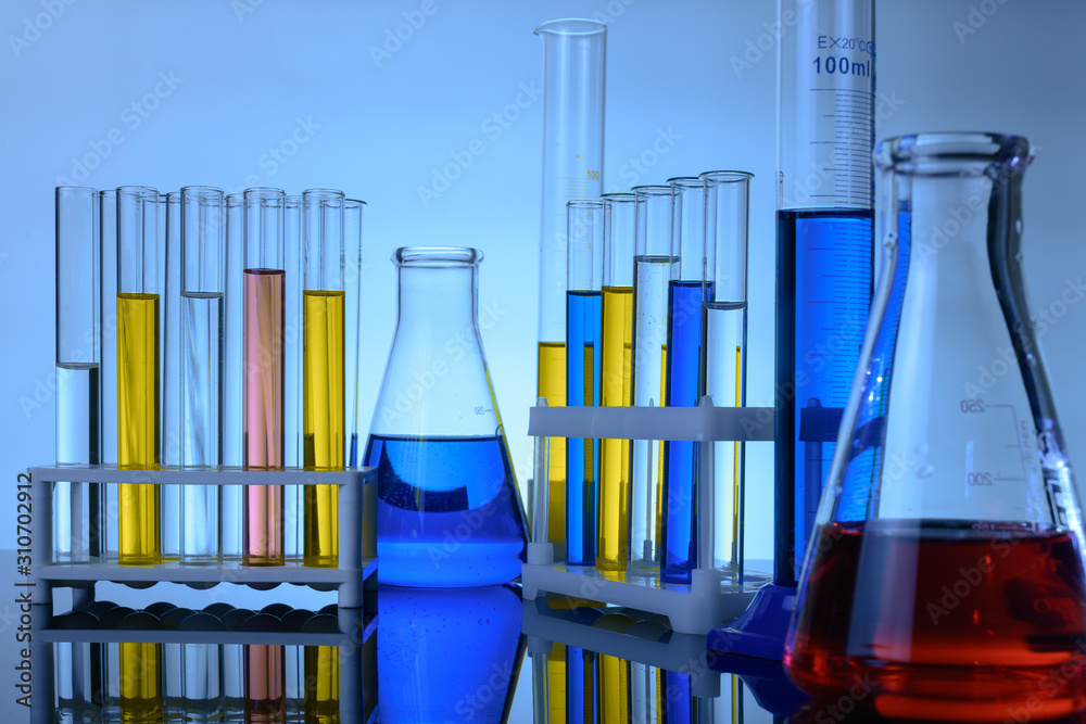 test tubes and flasks with colored liquids stand on a table in a ...