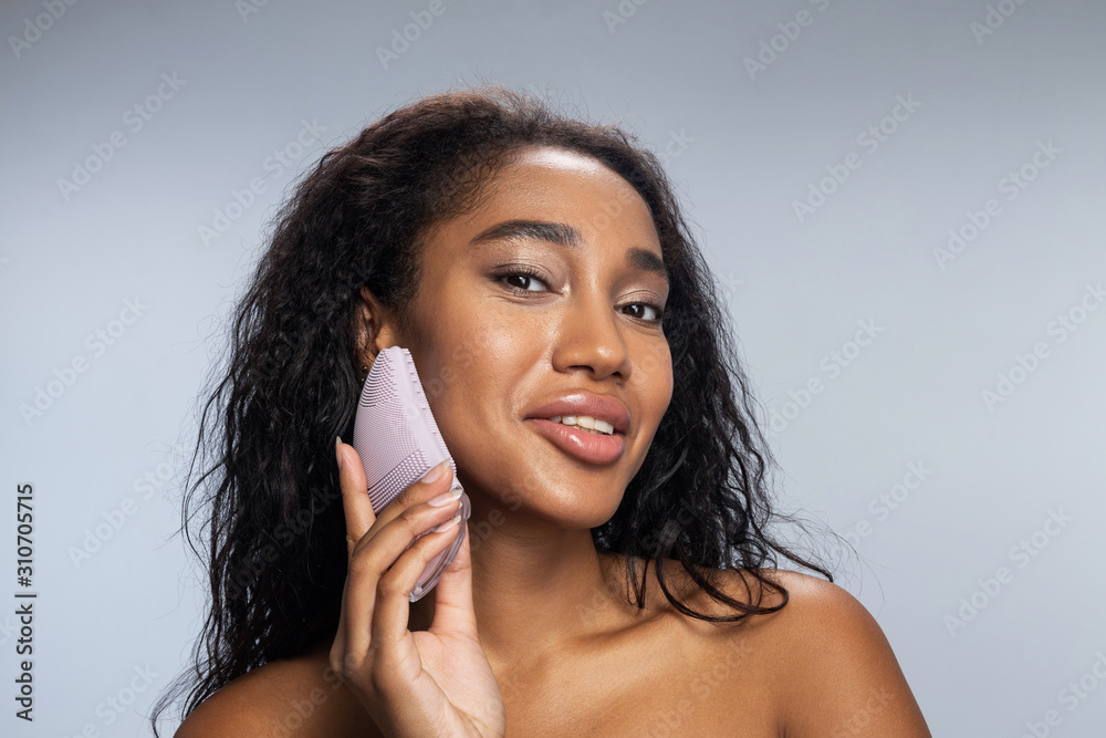 Attractive Afro American lady keeping silicone brush for face in her hand Attractive Afro American lady keeping silicone brush for face in her hand