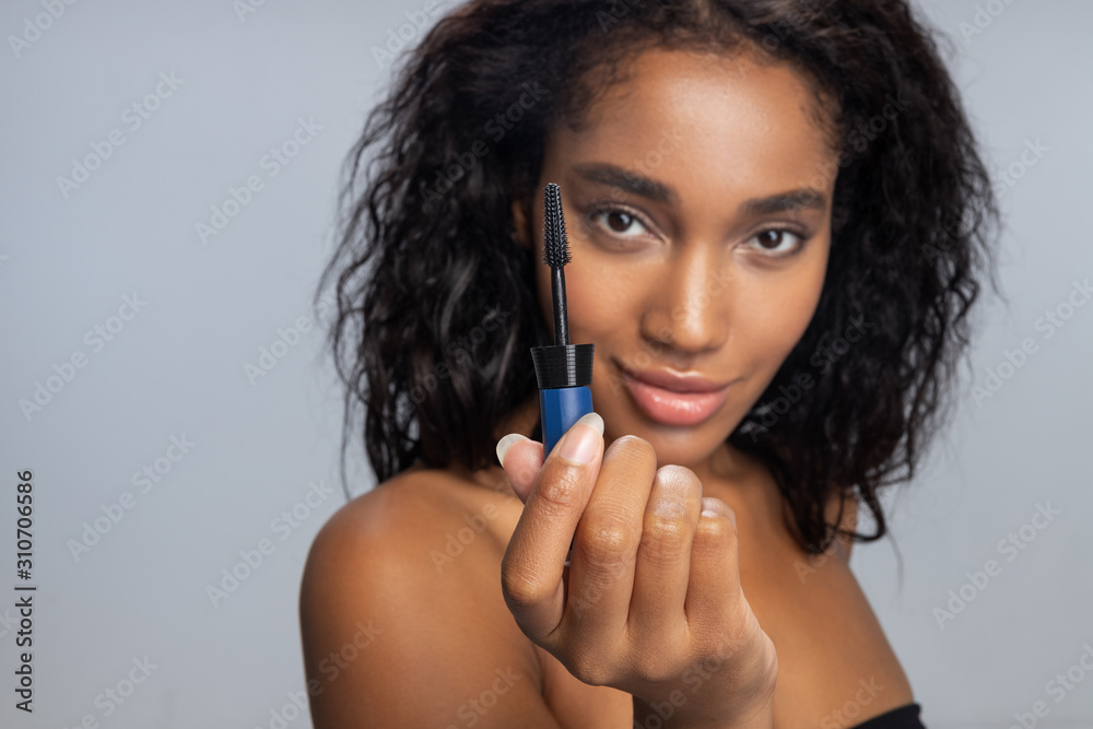 Pretty woman dyeing eyelashes with mascara against light background