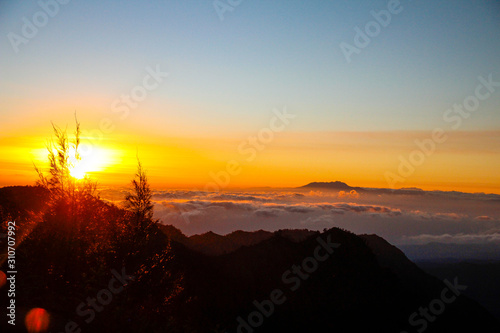 The sun rises above the clouds to the left of the Bromo volcano on the island of Java. Indonesia