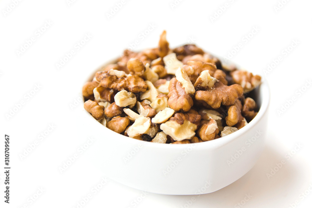 Peeled walnut kernels in white cup on white background. Healthy and organic food. Side view. Peeled walnut kernels in white cup on white background. Healthy and organic food. Side view.
