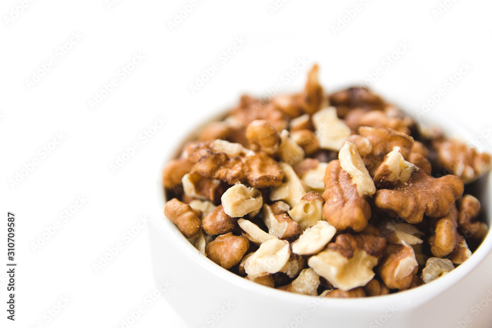 Peeled walnut kernels in white cup on white background. Healthy and organic food. Side view. Peeled walnut kernels in white cup on white background. Healthy and organic food. Side view.