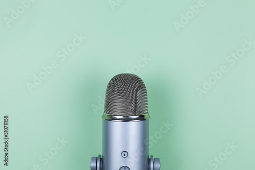 Closeup of professional microphone on mint background. Podcast studio concept. Electronic mic photo
