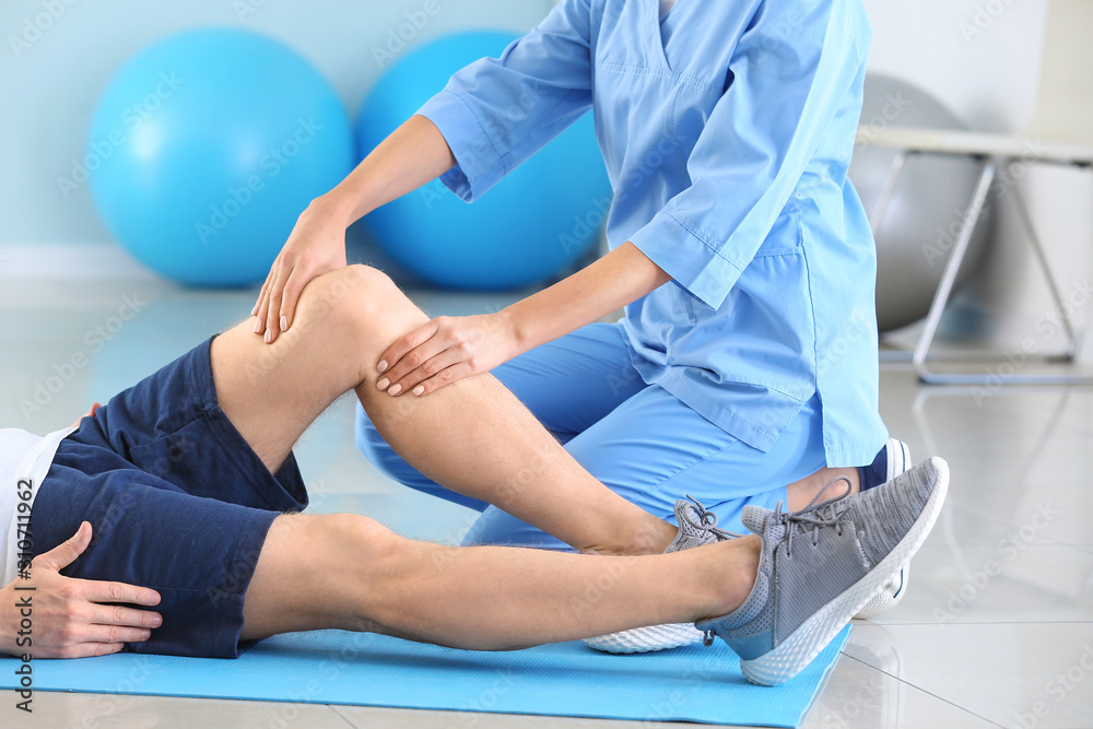 Physiotherapist working with male patient in rehabilitation center - obrazy, fototapety, plakaty 
