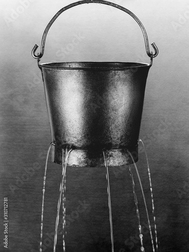 Water poring through holes in bucket (b&w)