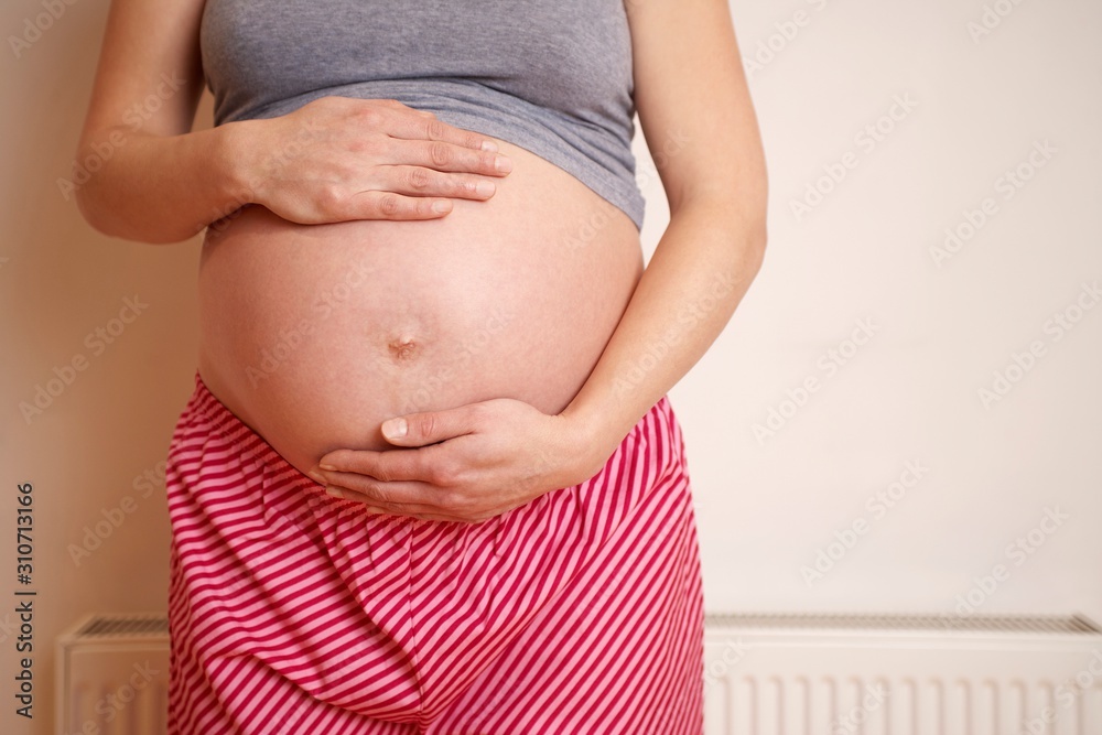 Midsection Of An Expectant Woman Touching Belly Midsection Of An Expectant Woman Touching Belly