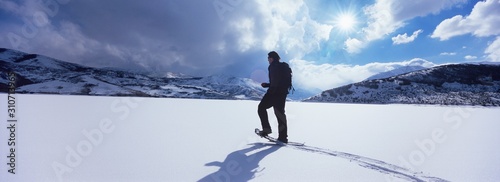 Man walking across snow in mountains photo