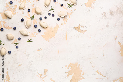 Raw dumplings with blueberries on white background