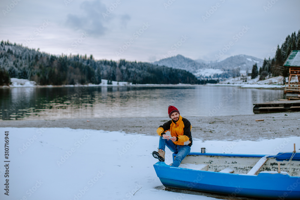 Young tourist man admire the amazing view of lake and mountain in the middle of winter with snowy forest , he is the elated of the landscape