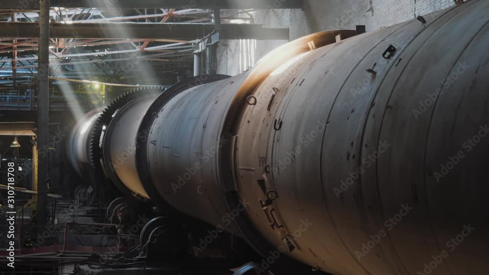 Rotary burning kiln on a cement plant. Industrial production process of cement clinker or expanded clay. Gears of rotation of a cylindrical furnace. Huge industrial oven on a factory. Rotary burning kiln on a cement plant. Industrial production process of cement clinker or expanded clay. Gears of rotation of a cylindrical furnace. Huge industrial oven on a factory.