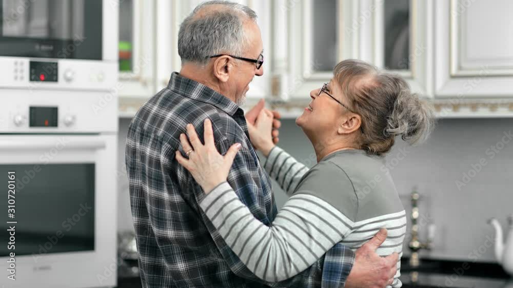 Happy aged couple having fun hugging dancing feeling love at kitchen Happy aged couple having fun hugging dancing feeling love at kitchen