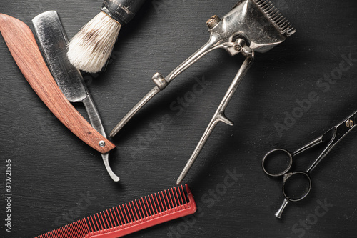 vintage barber tools dangerous razor hairdressing scissors old manual clipper comb shaving brush. old black background.