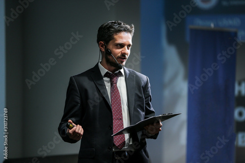 Attractive and confident successful man with headset speaking at corporate business coaching and training conference.Business and Entrepreneurship event,motivation training