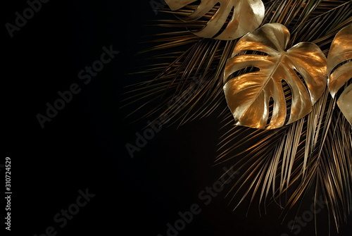 Gold leaves plant tropical monstera and palm pattern on a black background. t...