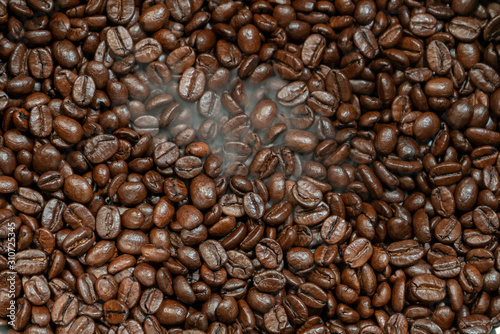 Roasted coffee beans with smoke close-up