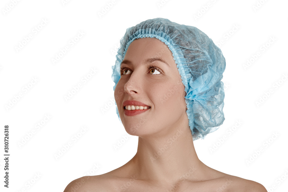 Beautiful girl in a medical cap of blue on a white isolated background. Beautiful young woman with clean fresh skin. Facial treatment. Cosmetology, beauty and spa. Skin care, close-up of the face