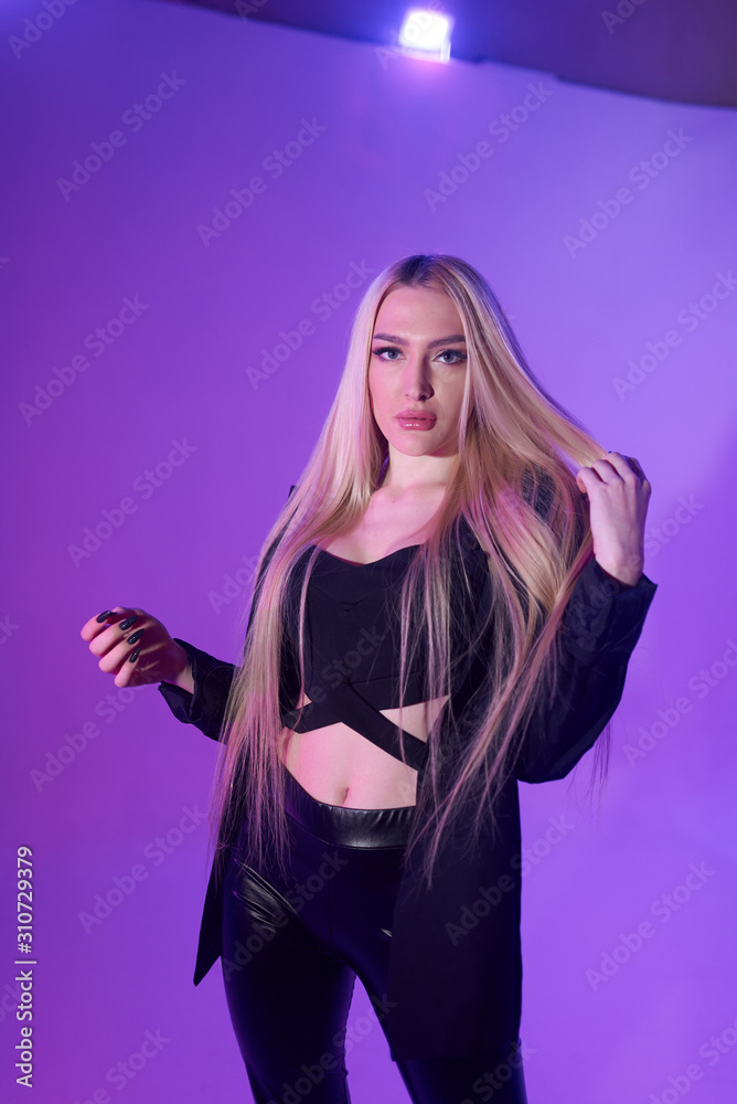 Attractive blonde woman sitting on the chair over pink background