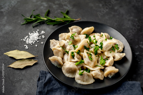 Dumplings with spices and herbs on a stone background with copy space for your text. Traditional Russian dish - dumplings photo