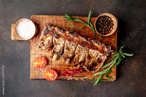Grilled pork ribs with spices on a cutting board on a stone background 