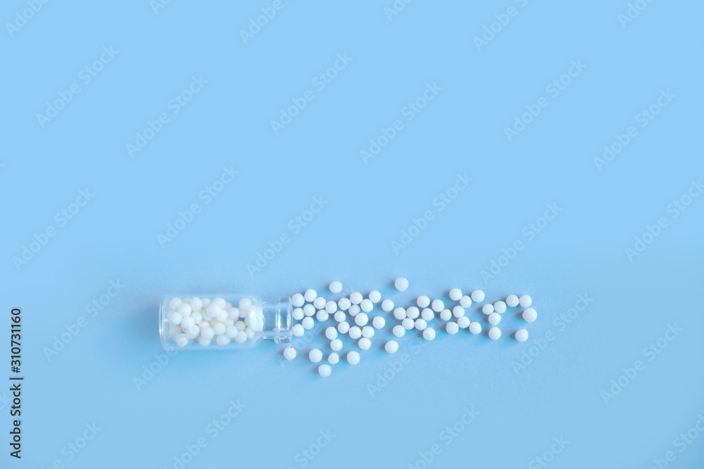 Homeopathy globules in glass bottles on a blue background. Alternative homeopathy herbal medicine, pills. Copyspace for text.