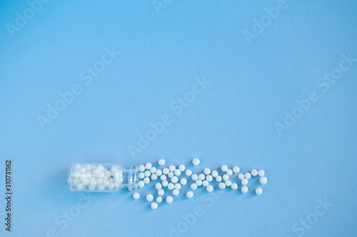 Homeopathy globules in glass bottles on a blue background. Alternative homeopathy herbal medicine, pills. Copyspace for text.