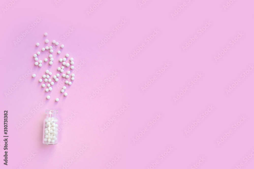 Homeopathy globules in glass bottles on a pink background. Alternative homeopathy herbal medicine, pills. Copyspace for text. Homeopathy globules in glass bottles on a pink background. Alternative homeopathy herbal medicine, pills. Copyspace for text.