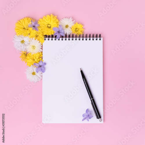 Feminine office workspace. Notebook with copyspace. Top View with Copy Space. Social media, wedding to do list concept. Beatiful flowers on pastel pink background.
