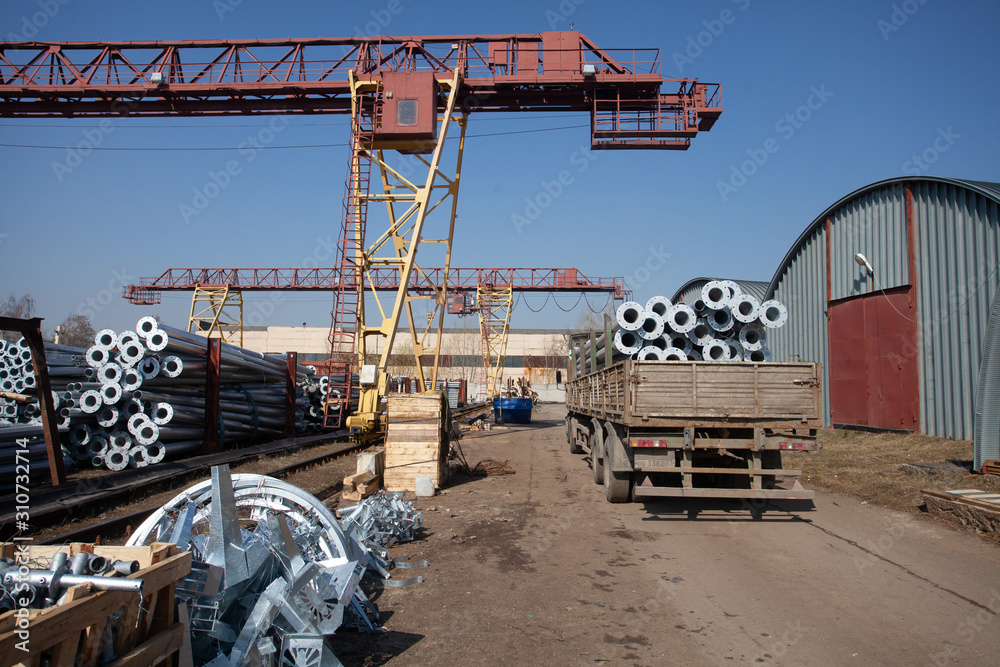 Metal warehouse outdoor of lighting poles. Storage of metal galvanized faceted pipes with flange. Metal warehouse outdoor of lighting poles. Storage of metal galvanized faceted pipes with flange.