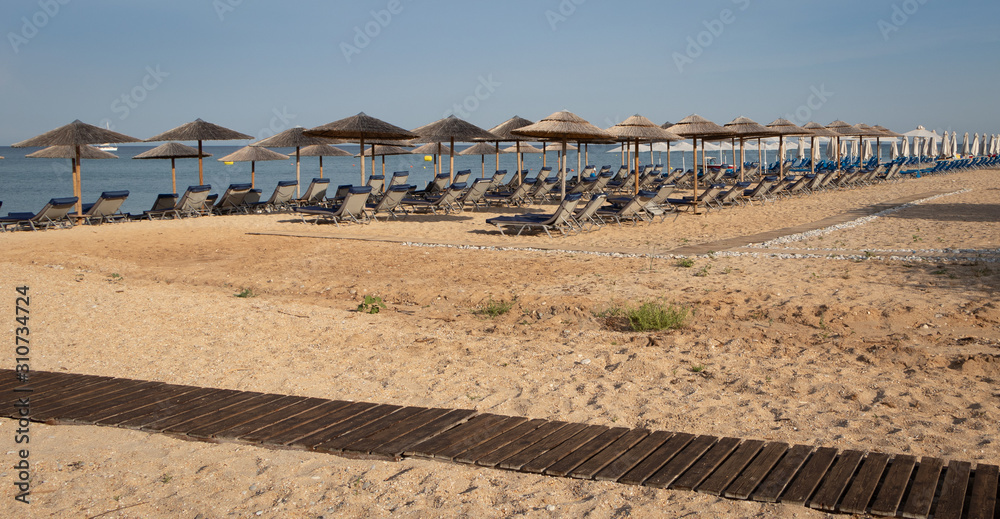 Rows of sunbeds and beach umbrellas waiting for tourists on the island of Kefalonia, Greece