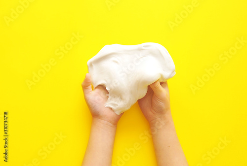 Child hands with slime on yellow background.