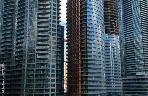 View of golden bank towers through slit in crowded highrise condominium construction in Toronto