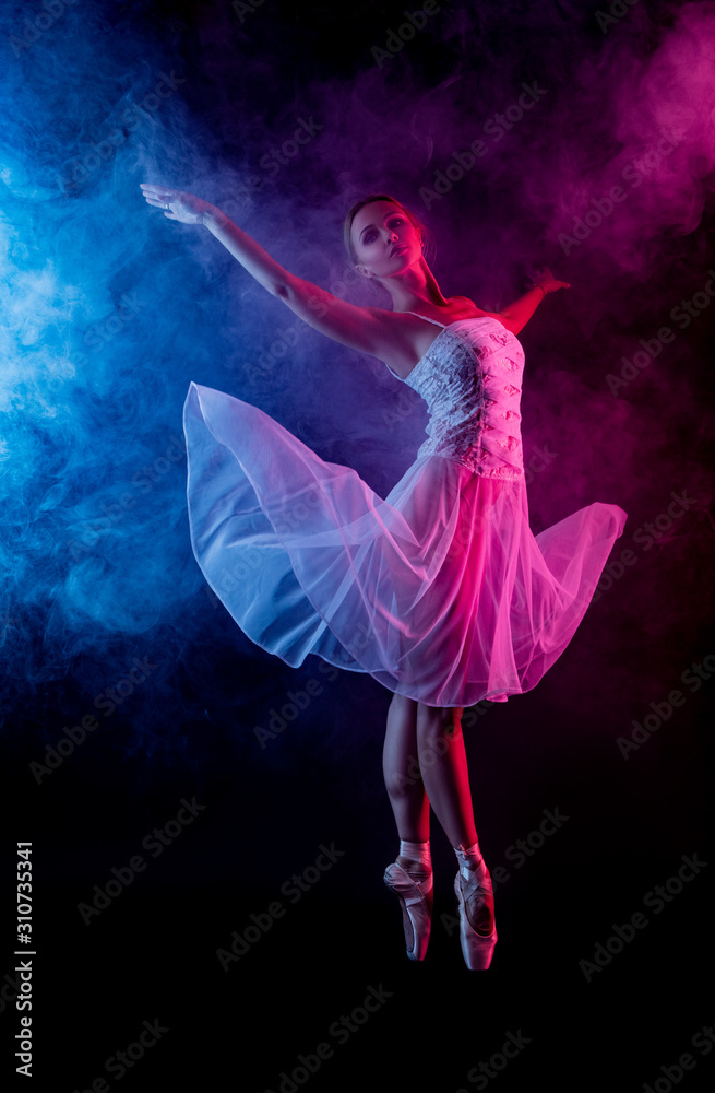 Ballerina dancing in colored smoke. dancer in motion with the effects of highlighting with color filters in the fog on a black background.     