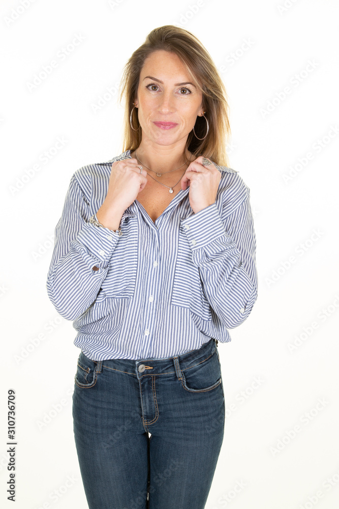 Smiling blonde haired dressed in blue blouse and jeans trousers stands on wall white background Smiling blonde haired dressed in blue blouse and jeans trousers stands on wall white background