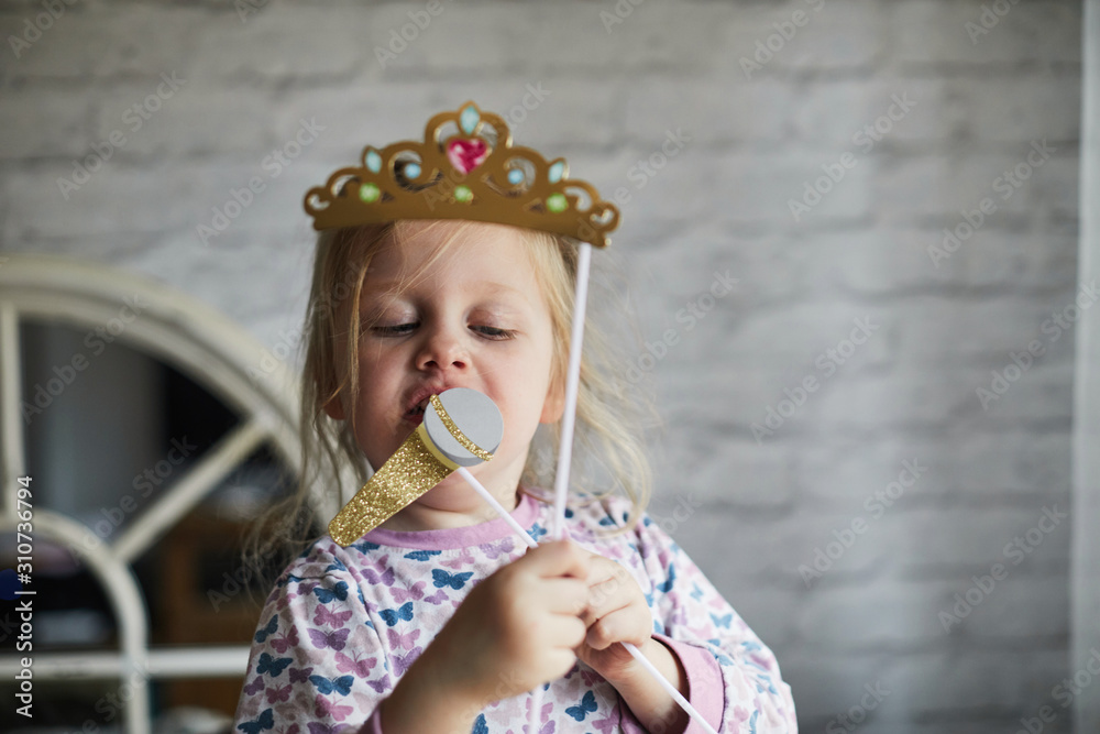 Child playing with a paper tiara and microphone Child playing with a paper tiara and microphone