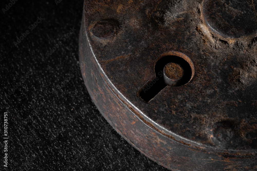 Old rusty vintage padlock on dark stone background. Macro shot. Close up, copy space
