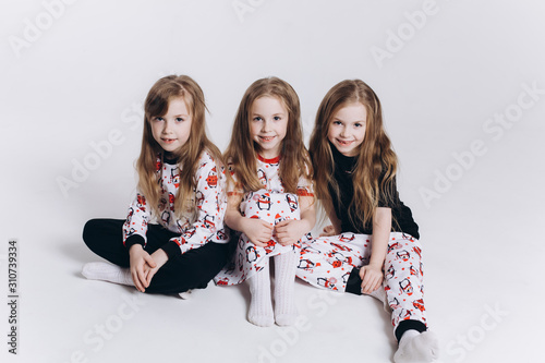 Happy cute adorable triplets girls posing in studio together on isolated background. Childhood, children, twins concept. Smiling girls playing together