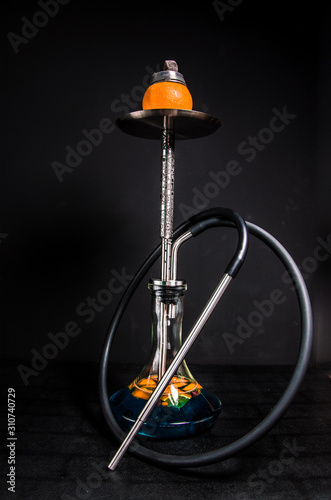 hookah on a grapefruit fruit, orange slices in a flask and blue syrup. beautiful metal shisha on black isolated background