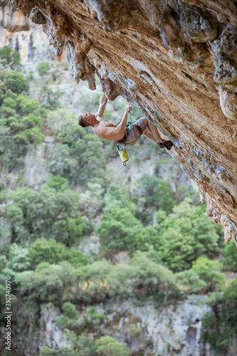 Young male rock climber on challenging route on cliff