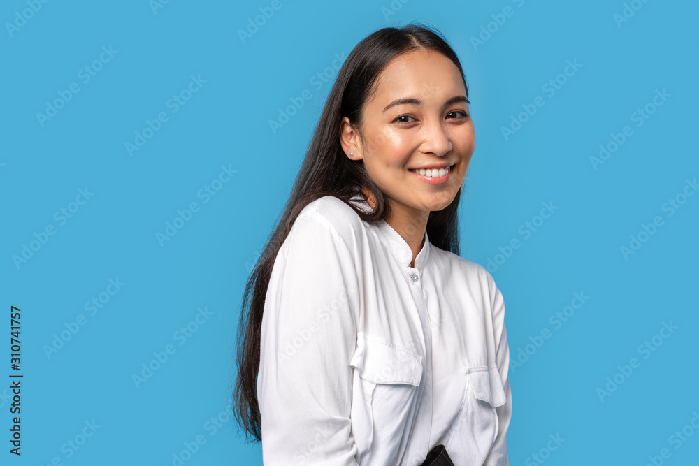 Freestyle. Young woman wearing shirt standing isolated on blue posing to camera smiling playful close-up Freestyle. Young woman wearing shirt standing isolated on blue posing to camera smiling playful close-up