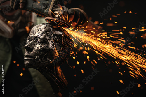 Artisan shaping metal bust with grinder photo