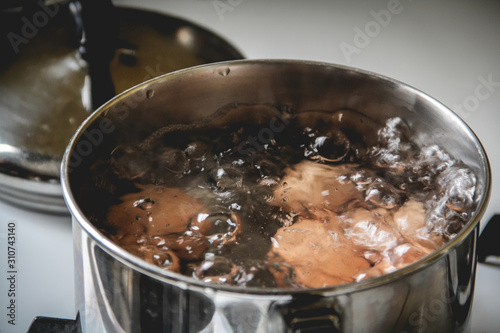 Brown eggs boiling in a small pot on the stove