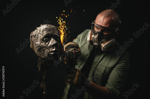 Artisan shaping metal bust with grinder photo