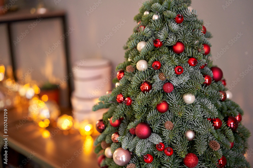 Beautiful small Christmas tree on wooden table. Happy mood. Garland lamp bokeh on background. Wallpaper. Danish pine and fir, Nobilis