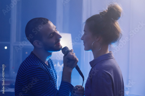 Happy man singing karaoke for girlfriend photo