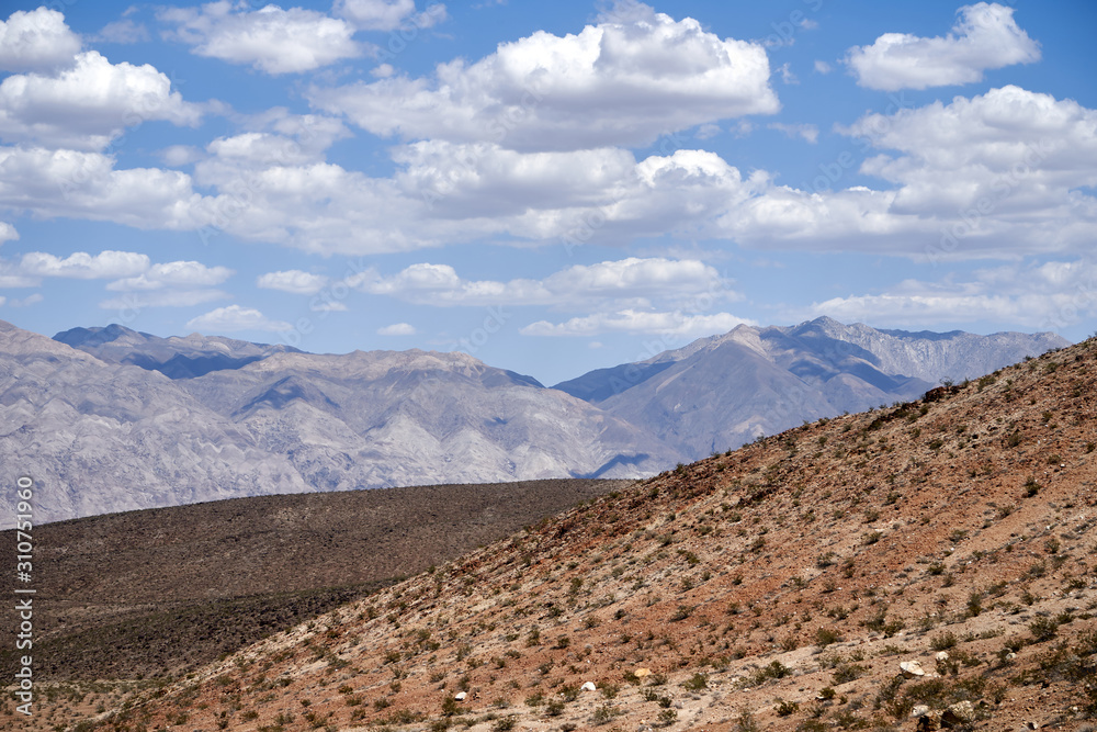 Mojave Desert. In southern California, southeast of Sierra Nevada, north and east of Los Angeles, North America. Rocks are brown and gray. Clouds in the blue sky