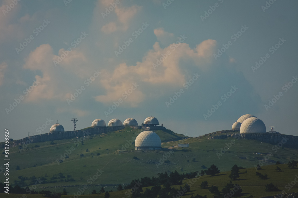 Army or radar stations on the top of the crimean high mountain plain. Radar domes are seen rising above the green plains on Ay Petri mountain. Army or radar stations on the top of the crimean high mountain plain. Radar domes are seen rising above the green plains on Ay Petri mountain.