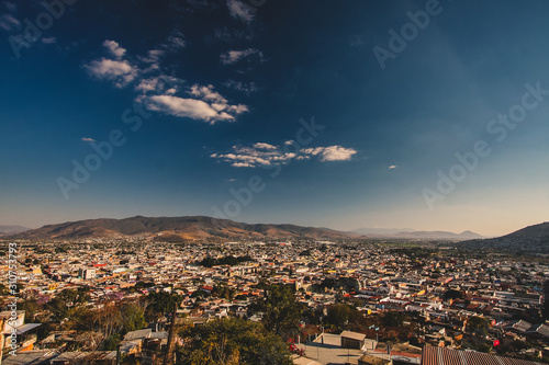 Panorama of Oaxaca, Mexico, on a sunny day with blue sky, looking from Benito Juarez statue above the city. Some white clouds are seen in the centre of the frame. © Anze