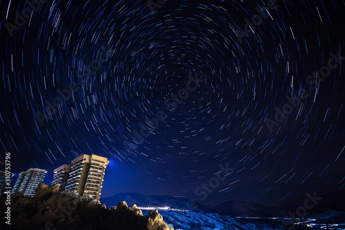 Star trail panorama over the apartment blocks in the ski village of Le Corbier, high in the French Alps around midnight. Star Polaris is seen in the center. photo