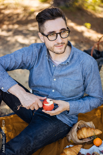 Human sitting on coverlet and cutting apple photo